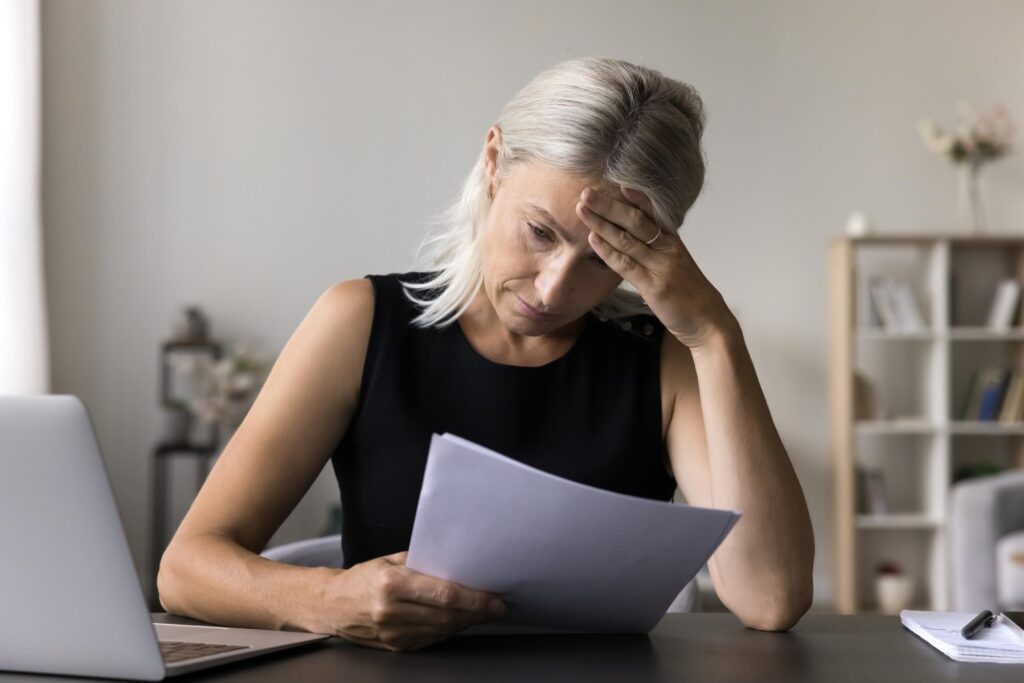 Older woman reviewing her credit report | How long does a timeshare foreclosure stay on your credit?